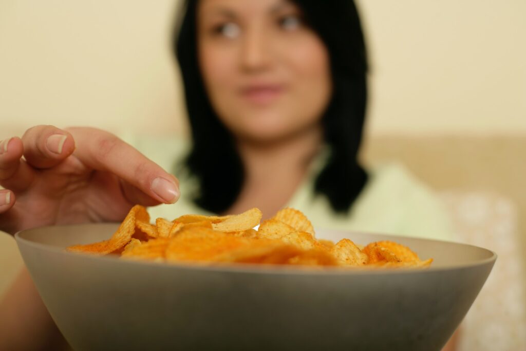 Hungry woman snacking on potato chips because she's hungry from relaxing too much on her weekend diet.